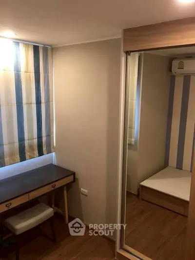 Cozy bedroom with mirrored wardrobe and study desk, perfect for compact living spaces.