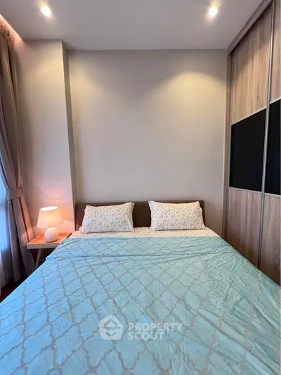 Cozy bedroom with elegant lighting and modern decor, featuring a comfortable bed and stylish wooden wardrobe.