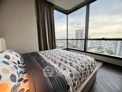 Luxurious bedroom with panoramic city view and elegant decor in high-rise apartment.