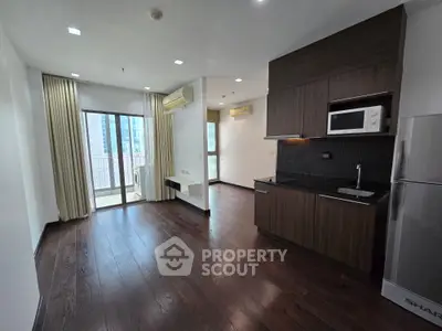 Modern apartment with open kitchen and balcony view, featuring sleek wood flooring and contemporary appliances.
