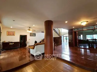 Spacious living room with wooden flooring and elegant staircase in a luxurious home.