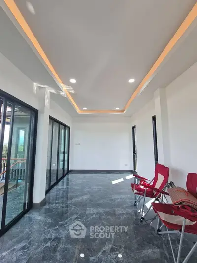 Spacious modern living room with sleek marble flooring and large windows for natural light.