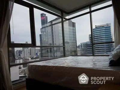 Spacious bedroom with panoramic city views through floor-to-ceiling windows, offering a serene urban retreat in a prime location.