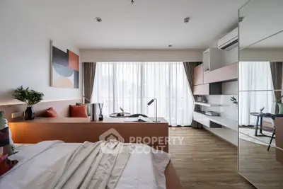 Modern bedroom with stylish decor and large windows offering city views, featuring a cozy workspace and elegant furnishings.
