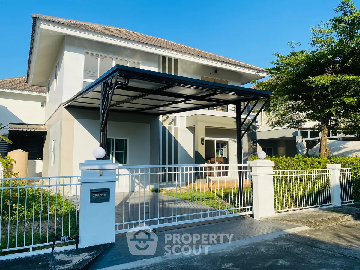 Modern two-story house with gated entrance and carport in a sunny suburban neighborhood.