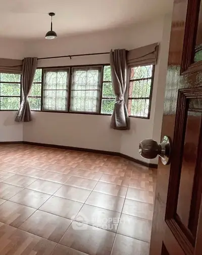 Spacious empty room with large windows and wooden flooring, perfect for customization.