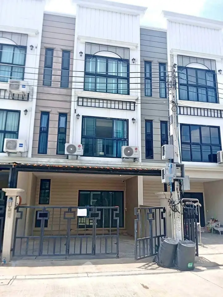 Modern townhouse exterior with gated entrance and multiple air conditioning units.
