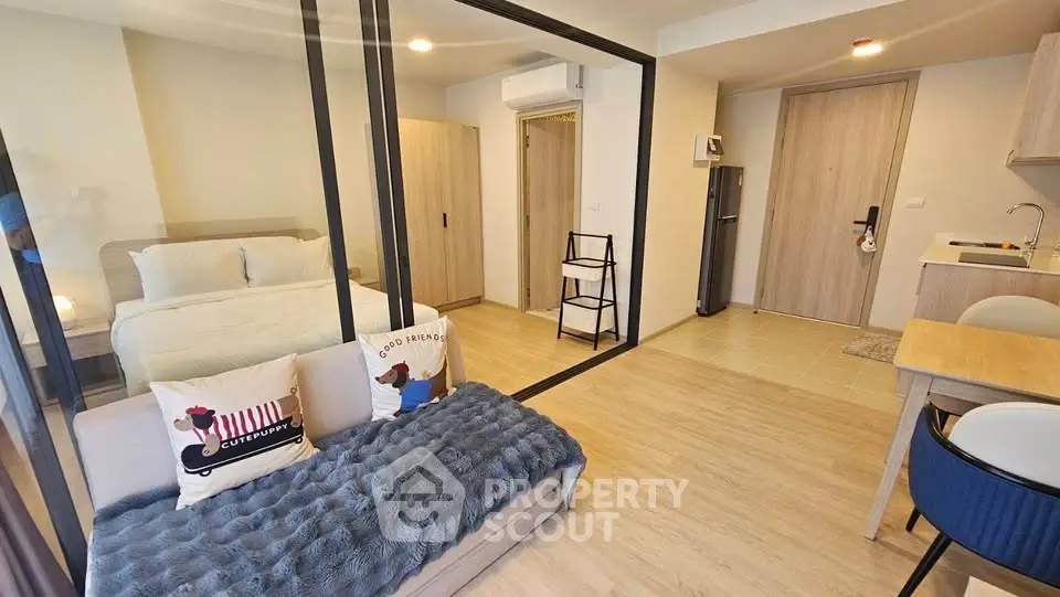 Modern studio apartment with glass partition, cozy living area, and compact kitchen.