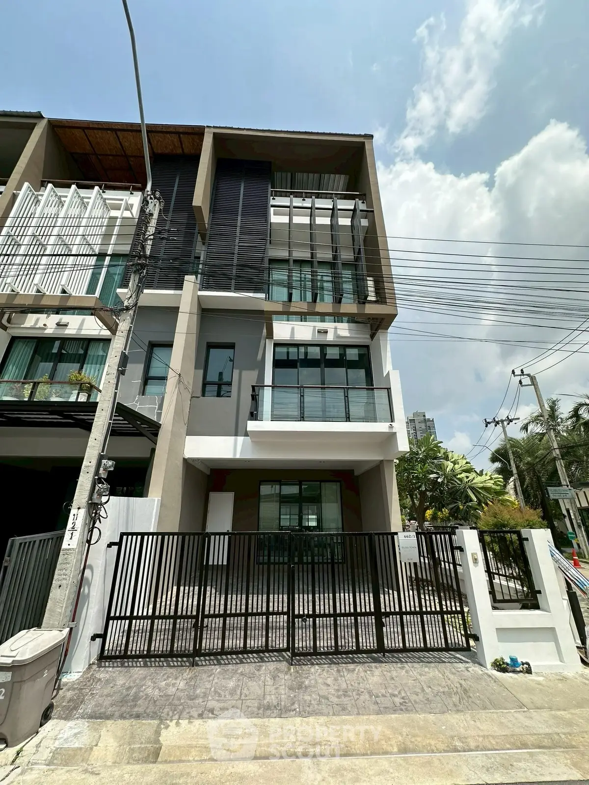 Modern multi-story townhouse with sleek design and gated entrance in urban setting.