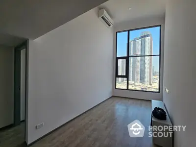 Spacious and sunlit living room with large windows offering an expansive city view, featuring high ceilings and modern wooden flooring, ideal for personalizing your dream urban space.