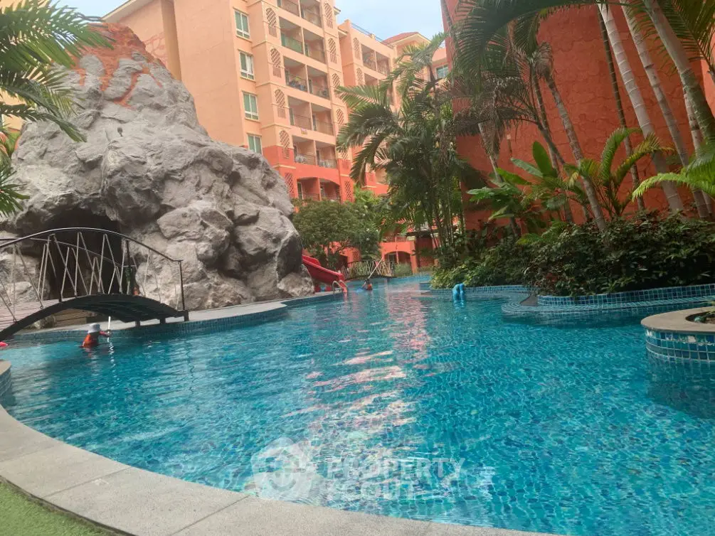 Luxurious resort-style pool with tropical landscaping and unique rock feature.