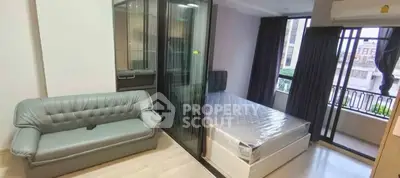 Modern studio apartment with glass partition, cozy sofa, and balcony view.