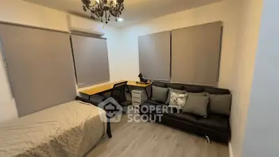 Cozy study room with bed, desk, and sofa, featuring modern decor and ample natural light.