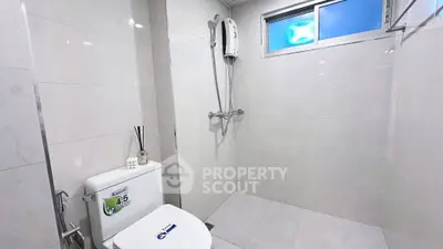 Modern bathroom with sleek shower and toilet in bright, minimalist design.