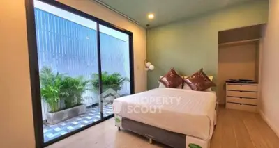 Modern bedroom with large glass doors opening to a private balcony with plants.