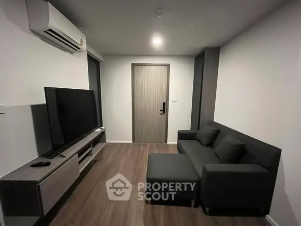 Modern living room with sleek furniture and large TV, ideal for urban living.