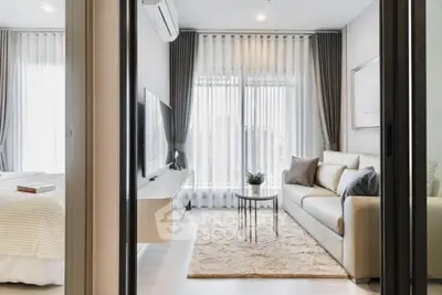 Modern living room with cozy sofa and large TV, featuring elegant curtains and natural light.
