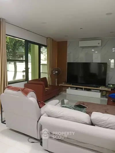 Spacious living room with modern furniture and large TV, perfect for relaxation.