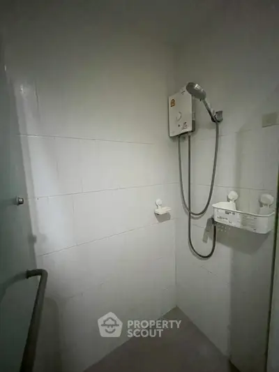 Compact bathroom with electric shower and white tiled walls