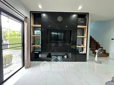 Modern living room with sleek black marble TV wall and large windows for natural light.