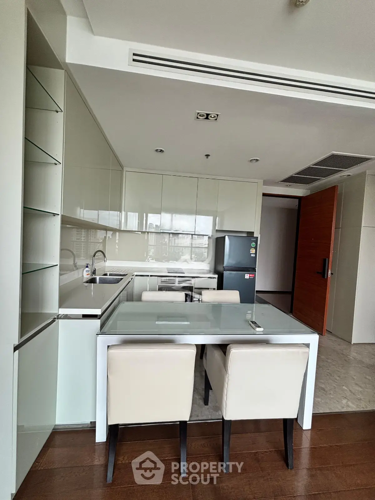 Modern kitchen with sleek design, featuring a glass dining table and built-in appliances in a stylish apartment.