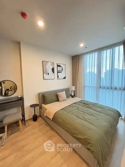 Modern bedroom with stylish decor and large window offering natural light.