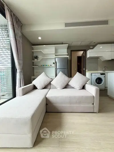 Modern living room with stylish sofa and open kitchen layout in a bright apartment.