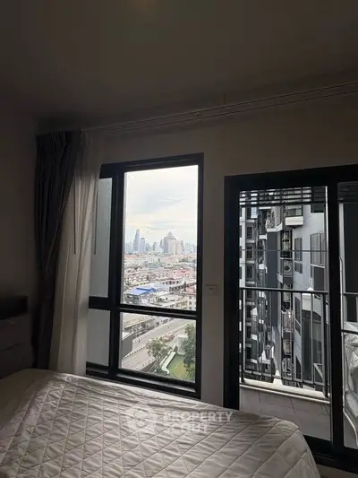 Modern bedroom with city view and balcony access in high-rise apartment