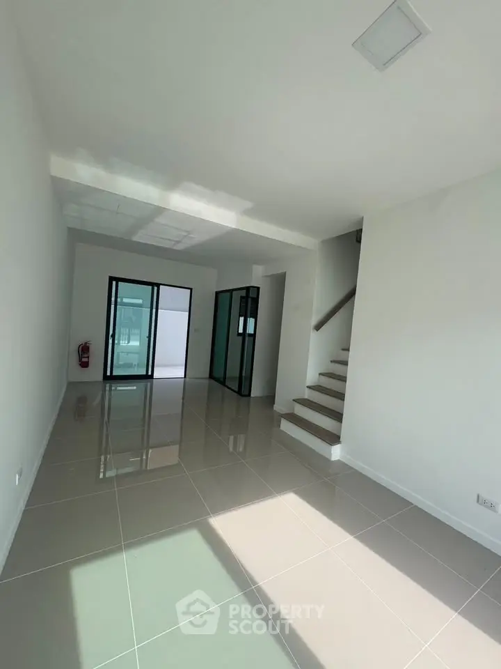 Spacious modern living room with glossy tiled floors and staircase