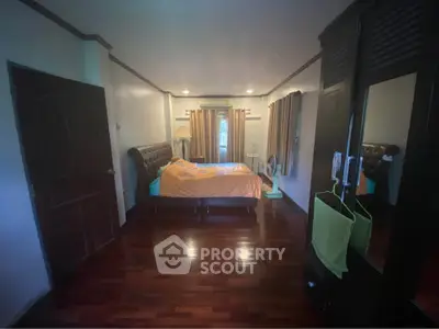 Spacious bedroom with elegant wooden flooring and stylish furnishings.