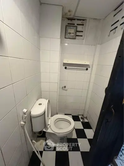 Compact bathroom with checkered floor tiles and white fixtures