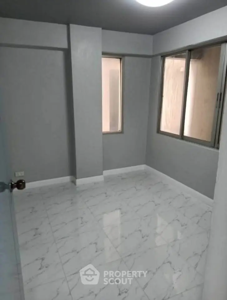 Spacious empty room with marble flooring and large windows in modern apartment.