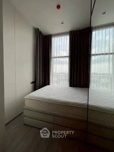 Cozy bedroom with large windows and modern design, perfect for urban living.