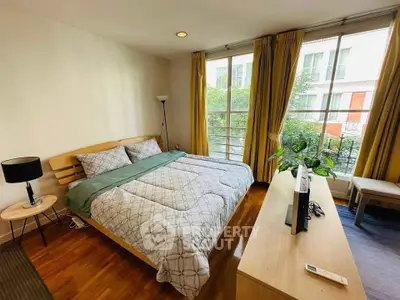 Spacious bedroom with large windows and modern decor in a stylish apartment.