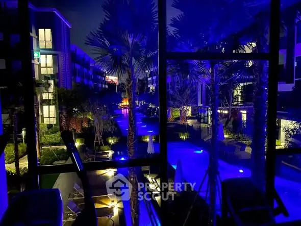 Stunning night view of modern apartment complex with illuminated pool and lush landscaping.