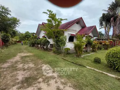 Charming countryside house with lush garden and red roof, perfect for serene living.