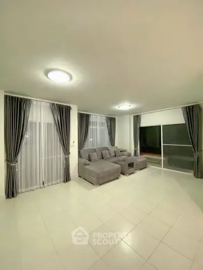 Spacious living room with modern gray sofa and large windows for natural light.