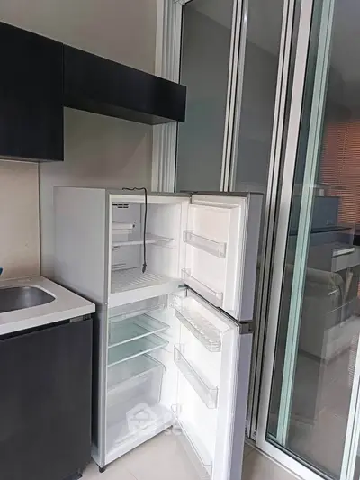 Modern kitchen with sleek fridge and sliding glass doors, perfect for urban living.
