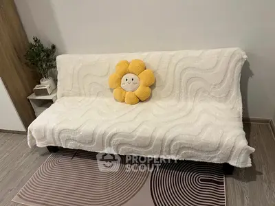 Cozy living room with a plush sofa and decorative flower pillow, perfect for relaxation.