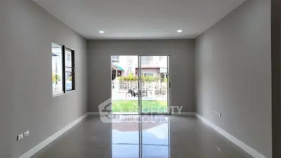Spacious unfurnished living room with large windows and sliding glass doors opening to a garden view.