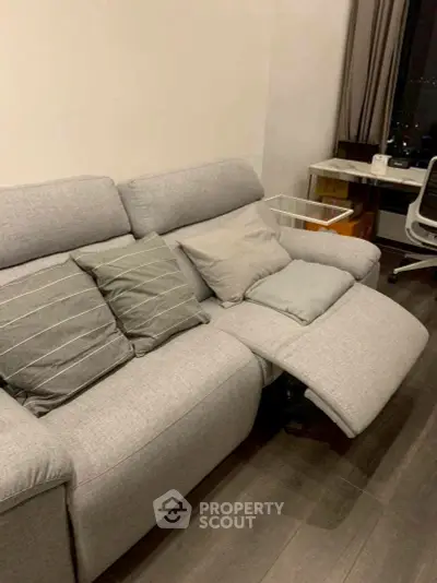 Modern living room with stylish gray sofa and sleek workspace setup.