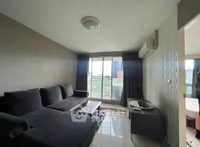 Modern living room with large windows and city view, featuring a sleek black sofa and stylish decor.