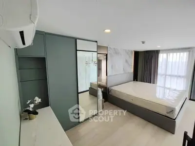 Modern bedroom with sleek design, large window, and built-in wardrobe in a stylish apartment.