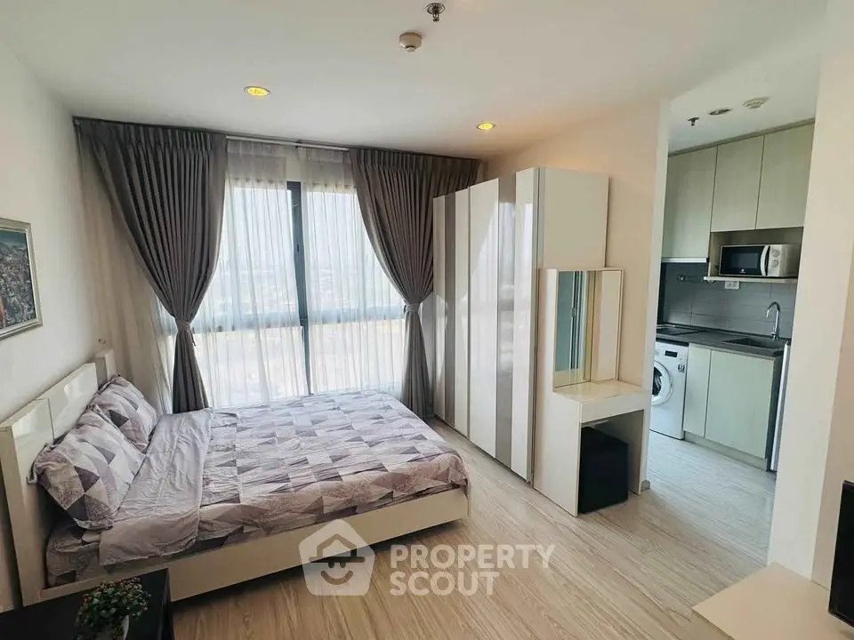 Modern bedroom with stylish decor and integrated kitchen appliances in a bright apartment.