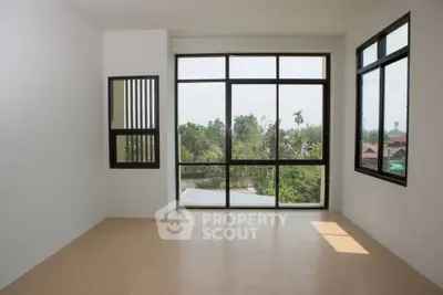 Spacious room with large windows offering a serene garden view, perfect for a bright and airy living space.