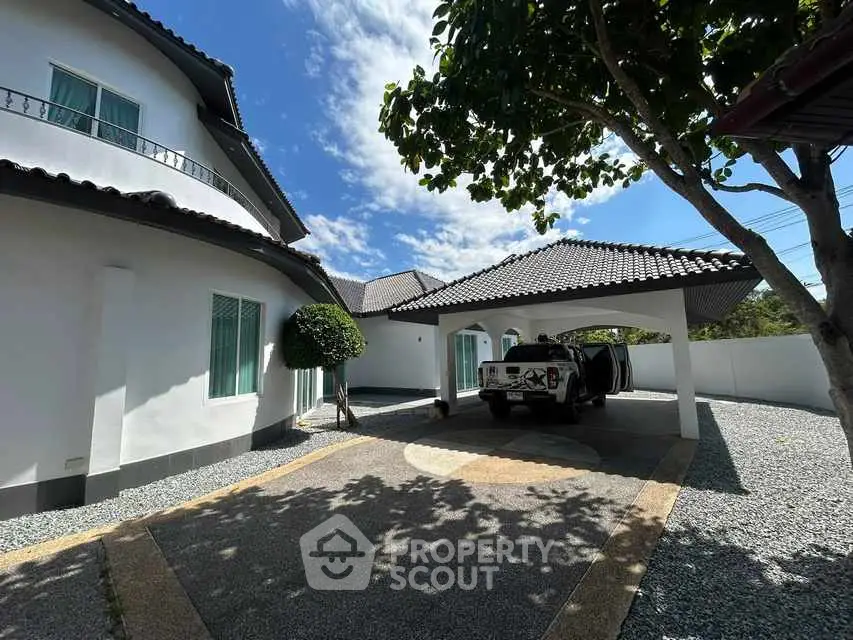 Charming suburban home with spacious driveway and lush greenery under a clear blue sky.