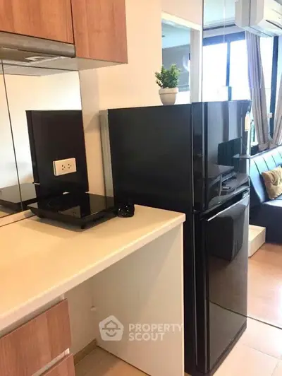 Modern kitchen with sleek black fridge and compact design in a stylish apartment.