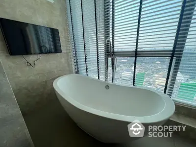 Luxurious bathroom with freestanding bathtub and city view through large windows.