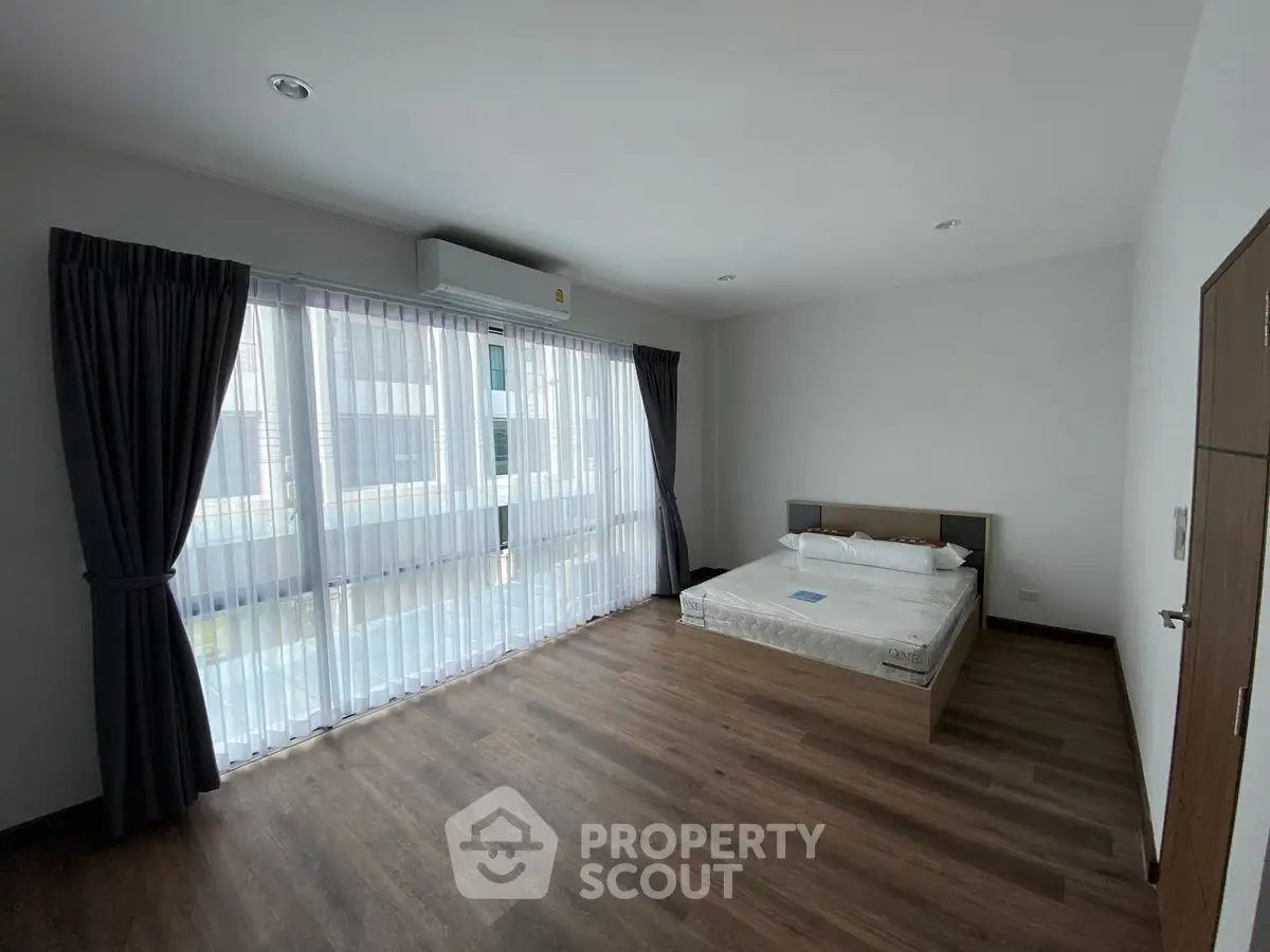 Spacious bedroom with large windows and modern wooden flooring