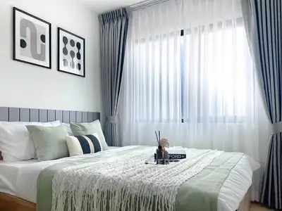 Elegant bedroom with modern decor, featuring a cozy bed, stylish curtains, and framed artwork, perfect for relaxation.
